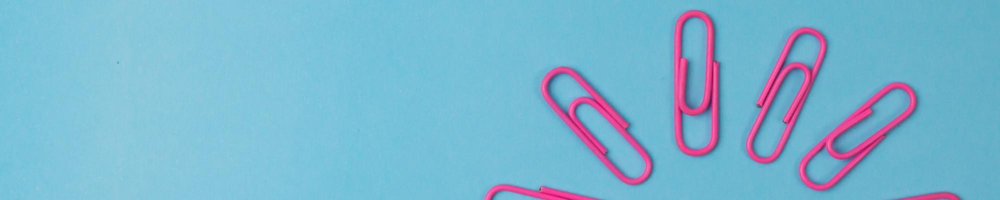 Composition of pink paper clips isolated on blue background